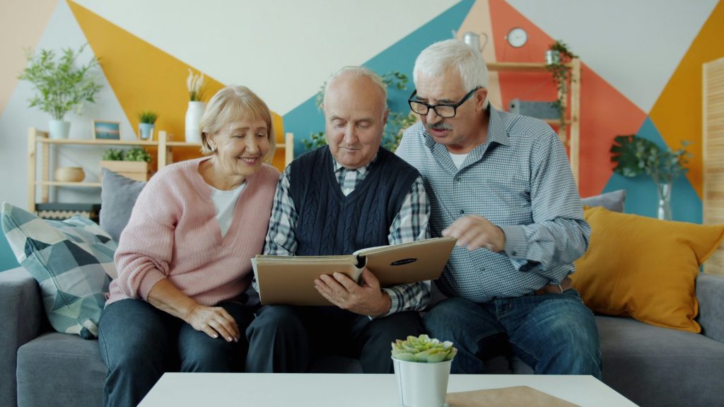 Three seniors looking at a photo album together.